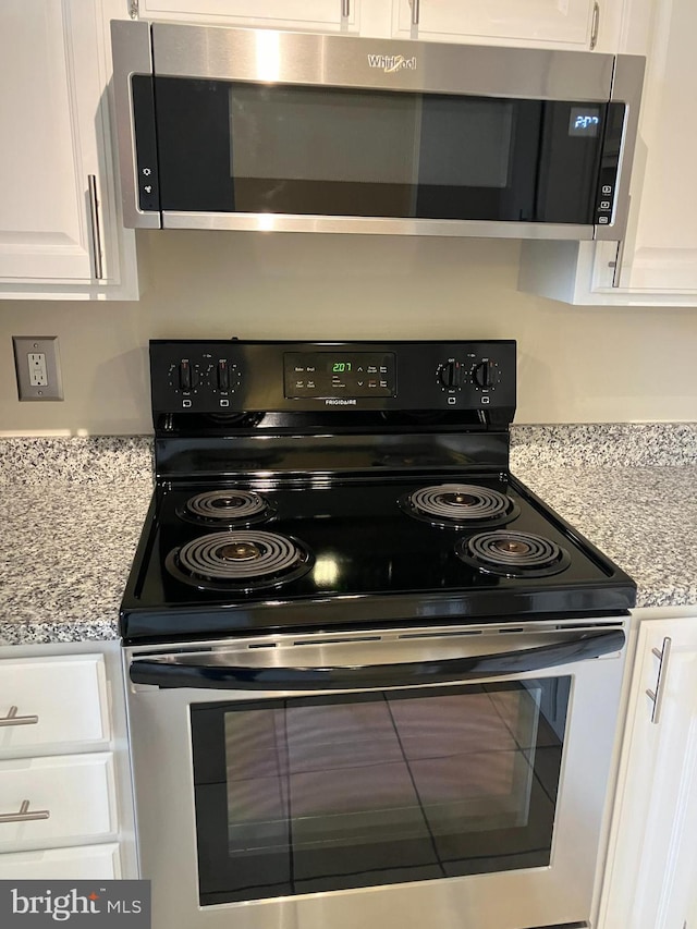 kitchen with electric stove, white cabinets, and light stone countertops