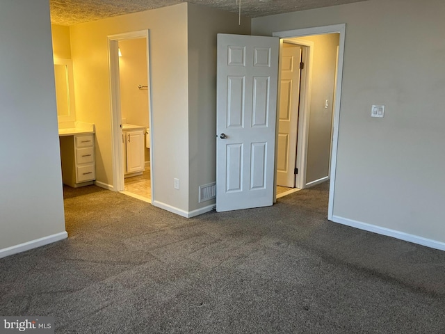 unfurnished bedroom with connected bathroom, a textured ceiling, and carpet flooring