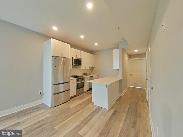 kitchen featuring stainless steel appliances, light hardwood / wood-style flooring, and white cabinets