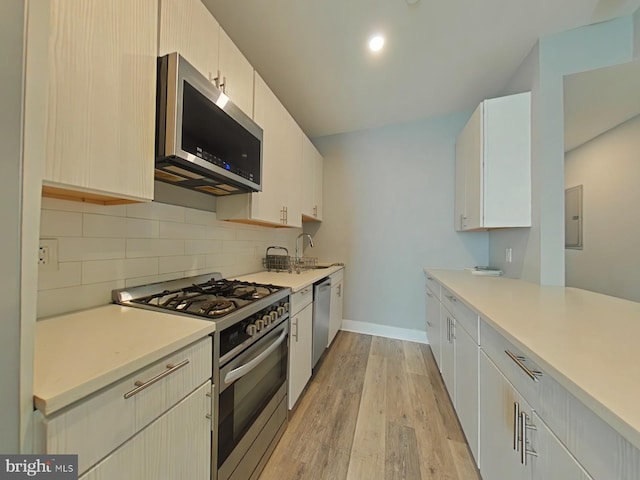 kitchen with appliances with stainless steel finishes, decorative backsplash, electric panel, light hardwood / wood-style flooring, and sink