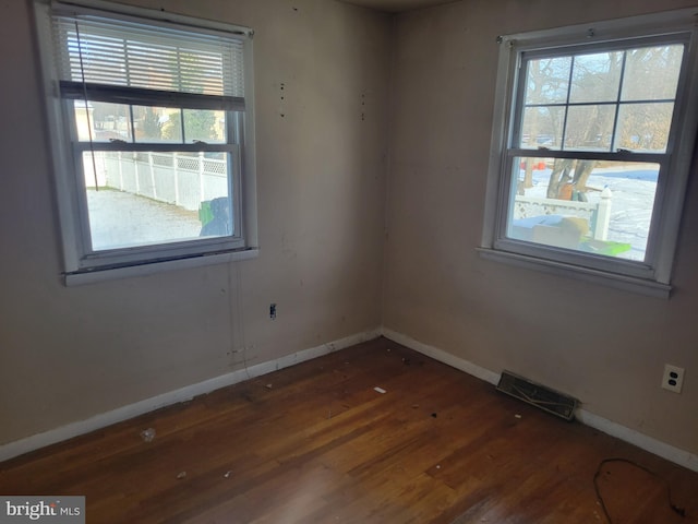 spare room featuring dark hardwood / wood-style flooring and a healthy amount of sunlight