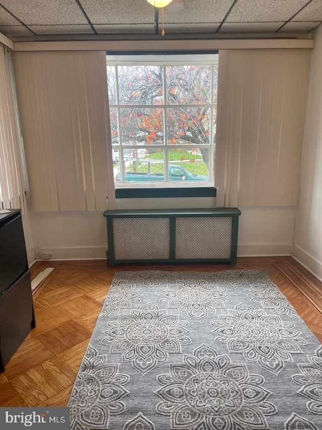 spare room with parquet flooring, radiator heating unit, and a paneled ceiling