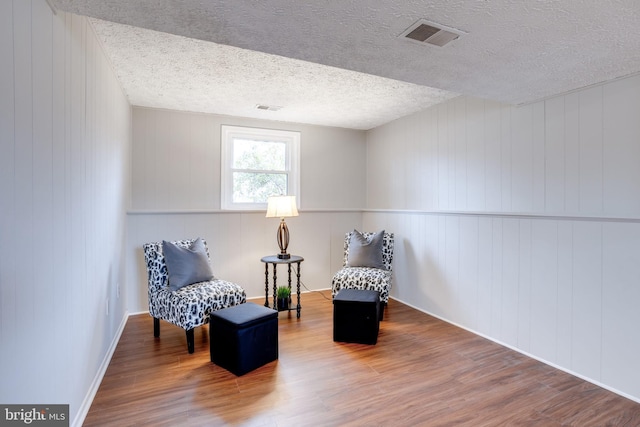 living area featuring wood-type flooring and a textured ceiling