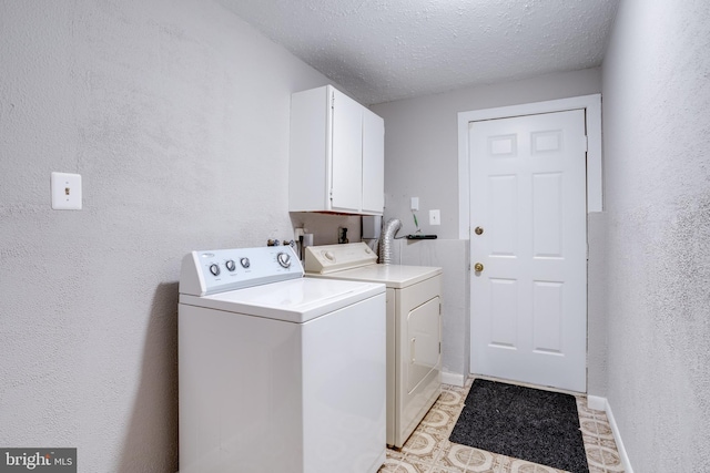 laundry area featuring washing machine and dryer, cabinets, and a textured ceiling