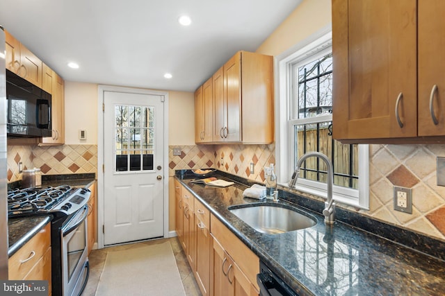 kitchen with sink, tasteful backsplash, light tile patterned floors, dark stone counters, and black appliances