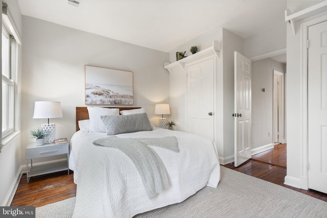 bedroom featuring multiple windows and dark wood-type flooring