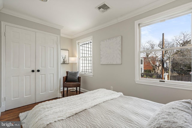 bedroom featuring multiple windows, hardwood / wood-style flooring, ornamental molding, and a closet