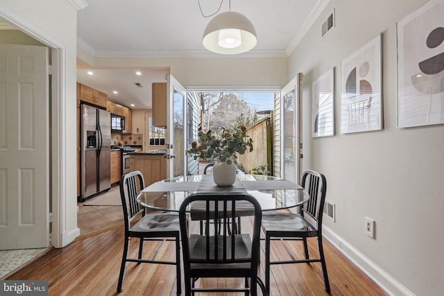 dining area with crown molding and light hardwood / wood-style floors