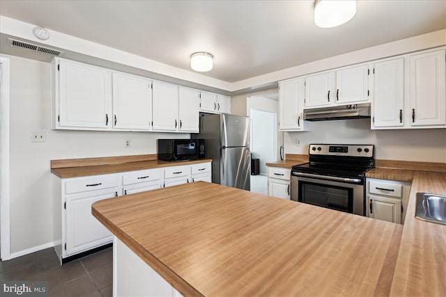 kitchen featuring stainless steel appliances, white cabinets, a peninsula, dark tile patterned flooring, and under cabinet range hood