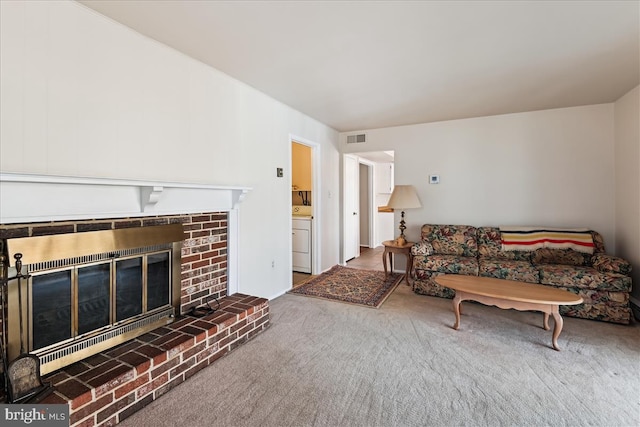 carpeted living room with washer / dryer, a brick fireplace, and visible vents