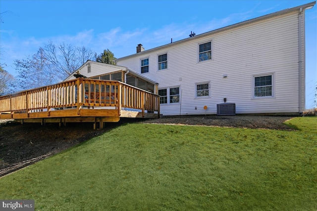 back of property with a lawn, a sunroom, a chimney, a deck, and central AC