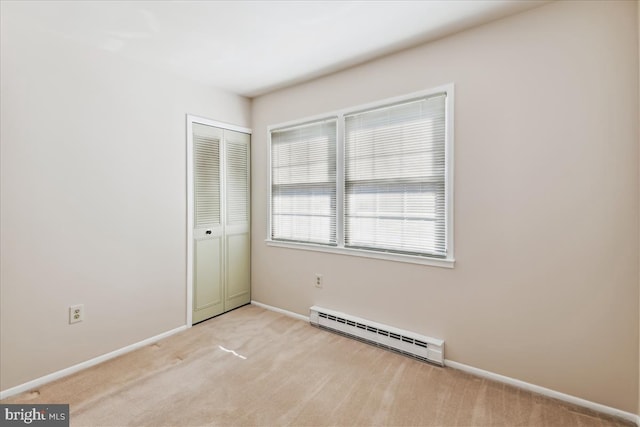 spare room featuring baseboards, light carpet, and baseboard heating