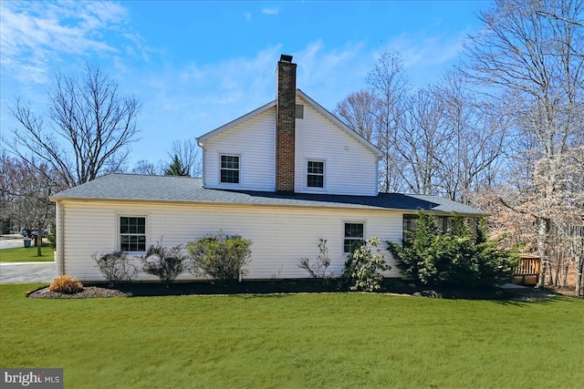 rear view of house with a deck, a yard, and a chimney