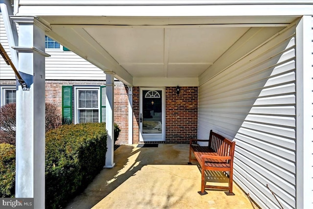 view of exterior entry with an attached carport and brick siding