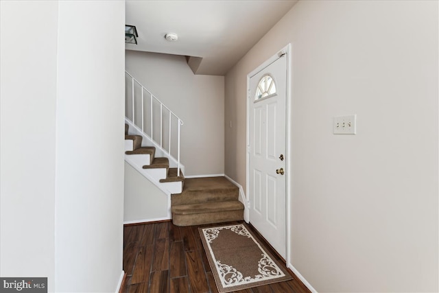 foyer entrance with stairs, baseboards, and wood finished floors