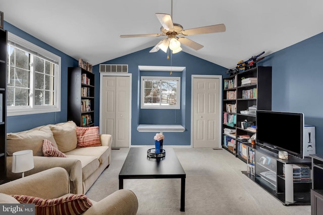 carpeted living room with ceiling fan, lofted ceiling, and plenty of natural light