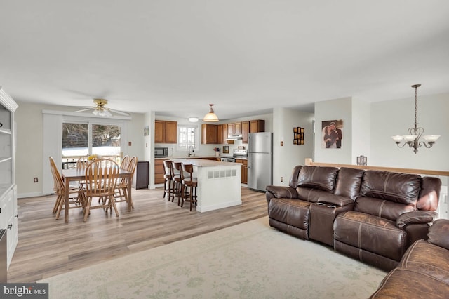 living room with sink, ceiling fan with notable chandelier, and light hardwood / wood-style flooring