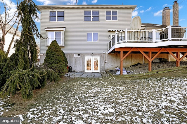 snow covered house featuring a deck and french doors