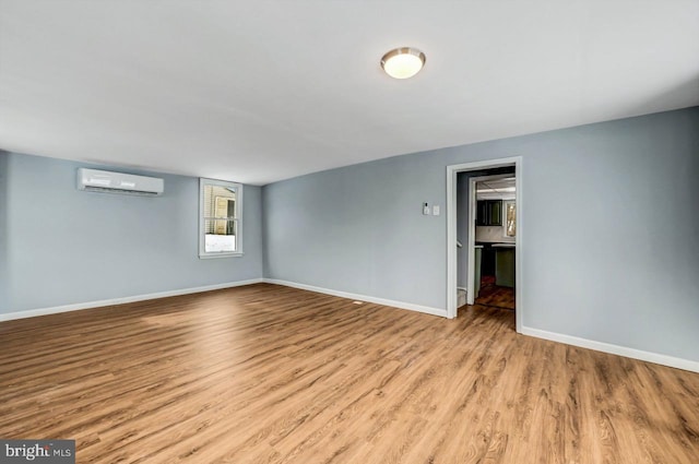 spare room featuring a wall mounted air conditioner and light hardwood / wood-style floors