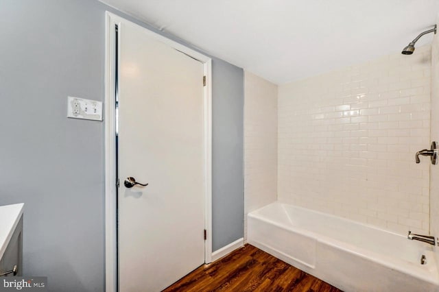 bathroom with hardwood / wood-style flooring, vanity, and tiled shower / bath