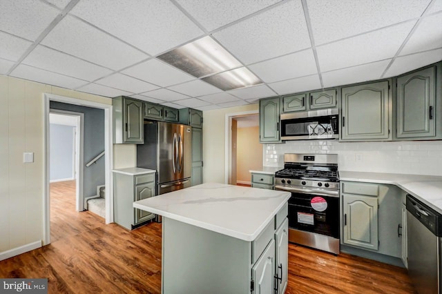 kitchen featuring stainless steel appliances, a kitchen island, green cabinetry, and a drop ceiling