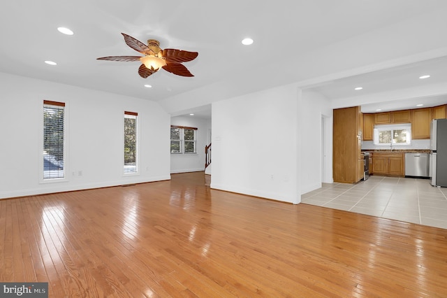 unfurnished living room featuring sink, ceiling fan, and light wood-type flooring