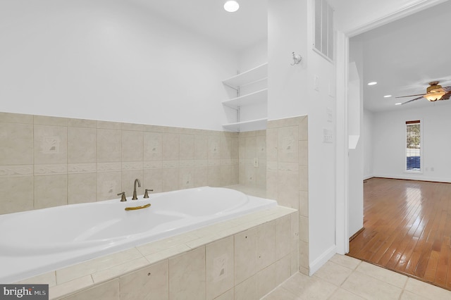 bathroom featuring ceiling fan, tile patterned flooring, and tiled tub