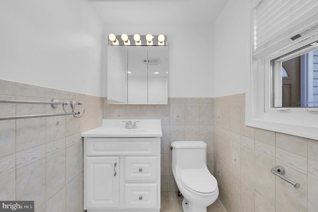 bathroom with vanity, tile walls, and toilet