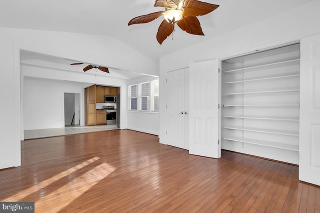 unfurnished living room with ceiling fan, wood-type flooring, and vaulted ceiling