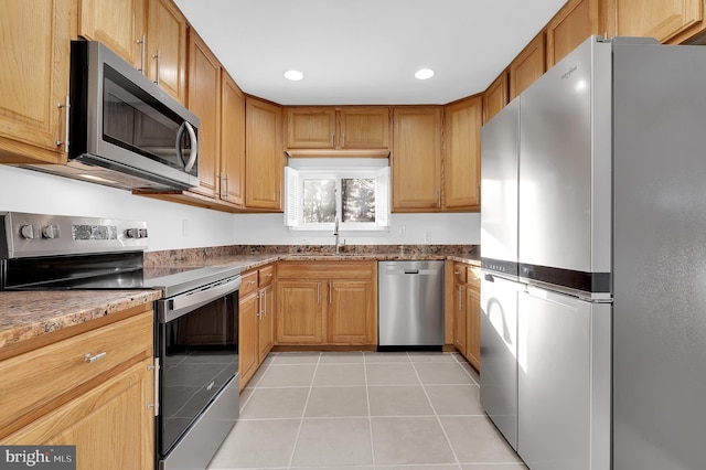 kitchen featuring stone counters, appliances with stainless steel finishes, sink, and light tile patterned floors