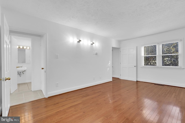 spare room with a textured ceiling and light hardwood / wood-style floors