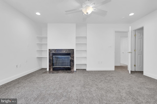 unfurnished living room with ceiling fan, a high end fireplace, and carpet flooring