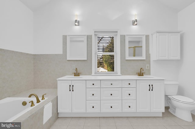 bathroom featuring vanity, tile patterned flooring, a relaxing tiled tub, and toilet