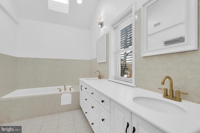 bathroom with vanity, a relaxing tiled tub, and tile patterned floors