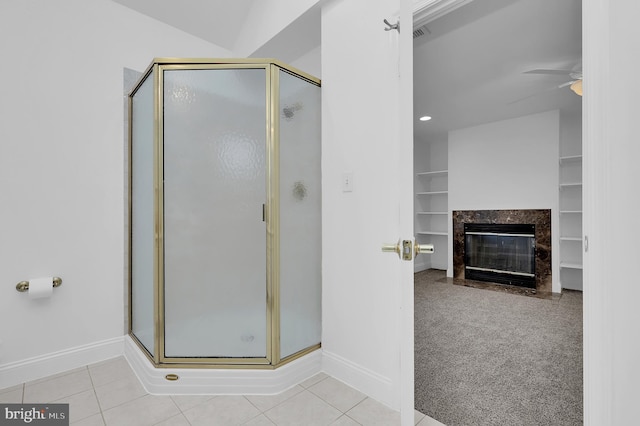 bathroom featuring lofted ceiling, a shower with shower door, ceiling fan, a high end fireplace, and tile patterned flooring