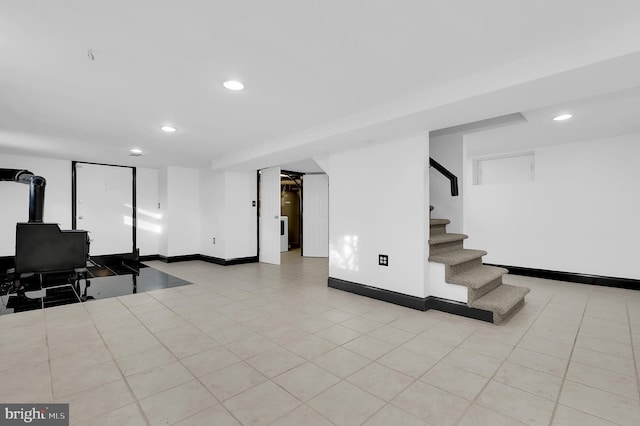 basement with a wood stove and light tile patterned floors