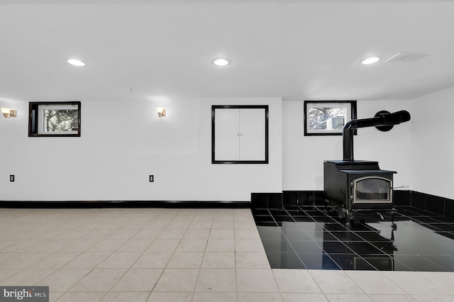 miscellaneous room featuring tile patterned flooring and a wood stove