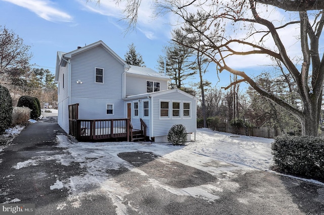 snow covered back of property with a wooden deck