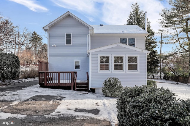 snow covered back of property with a wooden deck