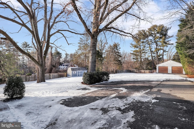 yard layered in snow with a garage and a shed