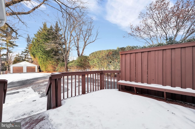 snow covered deck featuring a garage and an outdoor structure