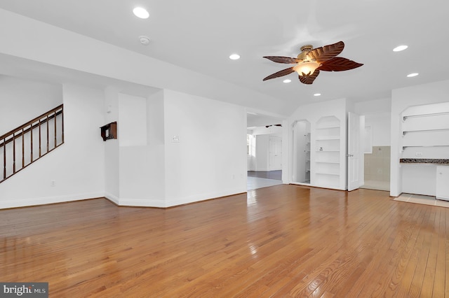 unfurnished living room featuring ceiling fan, built in features, and light wood-type flooring