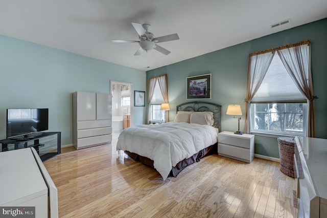 bedroom with ceiling fan, light hardwood / wood-style floors, multiple windows, and ensuite bath