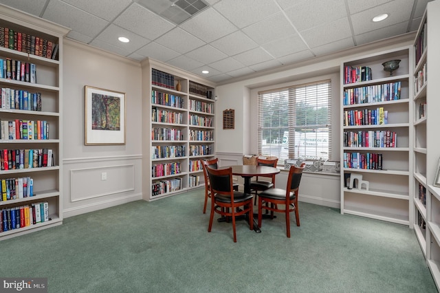 interior space with built in shelves, carpet, and a paneled ceiling