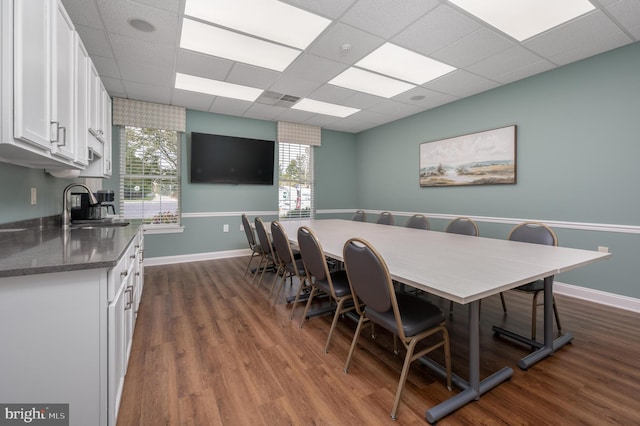 dining room with sink, dark hardwood / wood-style floors, and a paneled ceiling