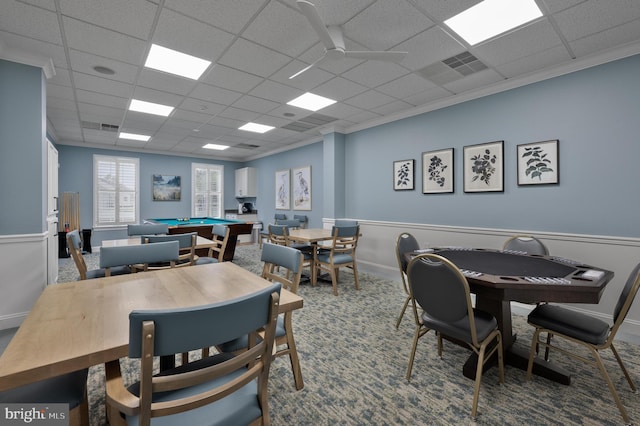 carpeted dining area with ceiling fan, ornamental molding, and a drop ceiling