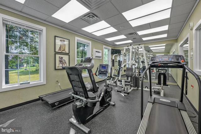 workout area with an AC wall unit and a drop ceiling