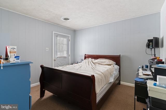 carpeted bedroom with a textured ceiling and wood walls