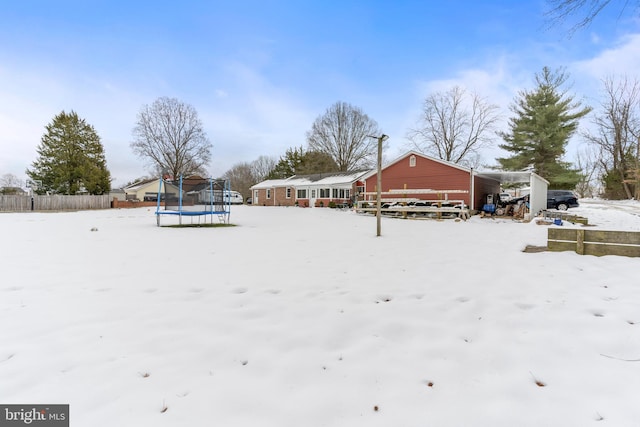 yard layered in snow with a trampoline