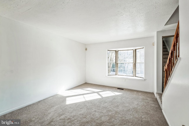 empty room featuring light carpet and a textured ceiling